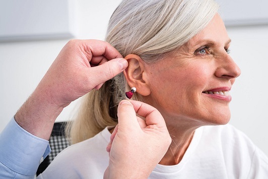 Ältere Frau erhält ein modernes Hörgerät zur Verbesserung ihres Hörvermögens im Ohr.